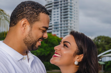 Fototapeta premium couple of young latin american men and women and happy in an outdoor portrait, together in a park, ju both romantically laughing and hugging
