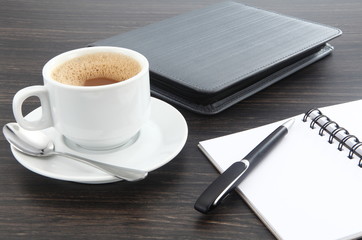 cup of coffee and pen on notebook