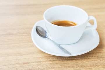Black coffee in white cup on wooden background.