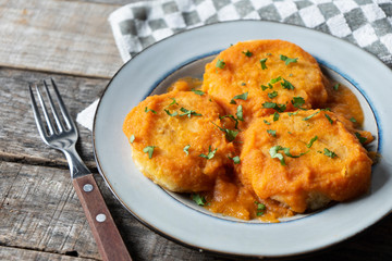 Mexican potato patties with red sauce on wooden background