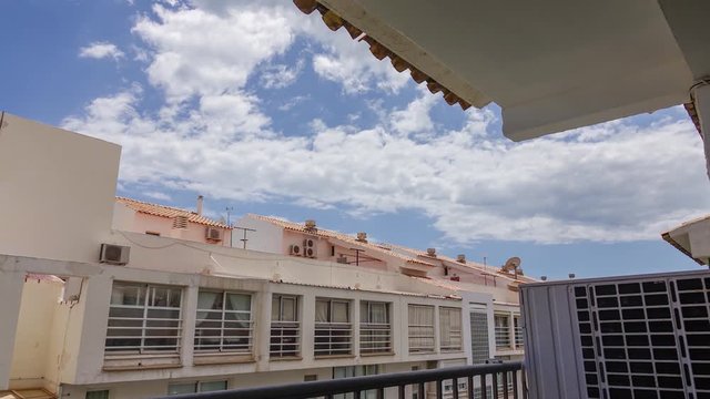 Clouds passing over apartment buildings seen from a balcony. Zooming in.