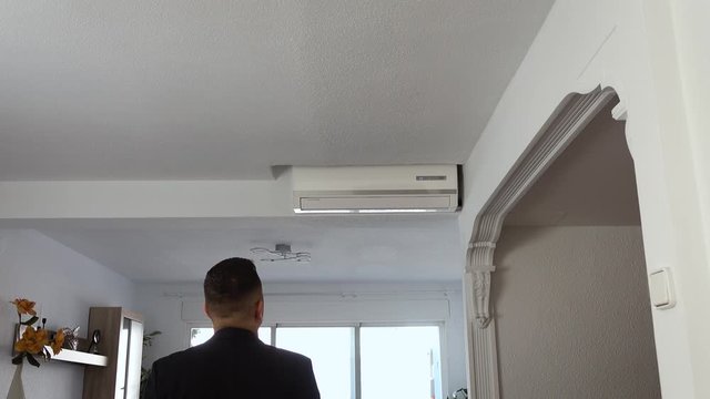 Male turning on air conditioning unit with remote control.