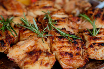 Сlose up chicken thighs fried on a barbecue , with rosemary branches .