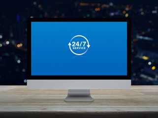 24 hours service flat icon on desktop modern computer monitor screen on wooden table over blur colorful night light city tower and skyscraper, Business full time service online concept