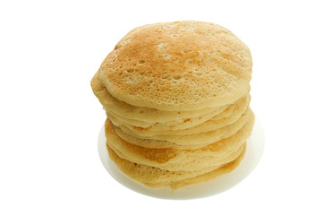 Pancakes on a plate isolate. A large stack of lush rosy pancakes on a white plate on an isolated surface.