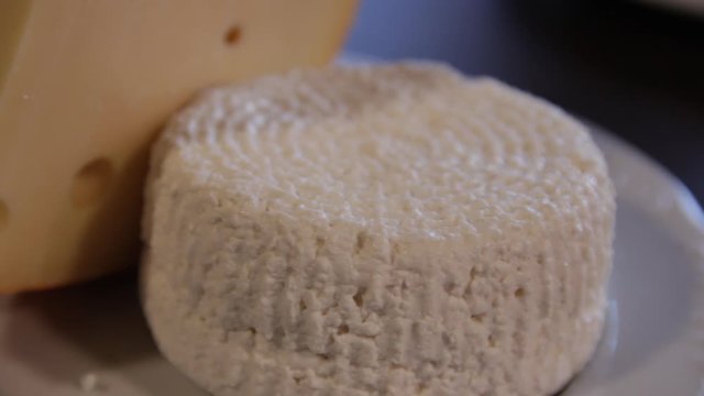 plate on the table with Emmental and Adygei cheese. camera moves around it. close-up.macro.