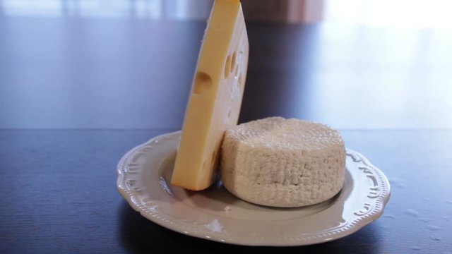 plate on the table with Emmental and Adygei cheese. camera moves around it.
