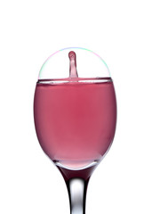 Colored water drop splash inside of  soap bubble on crystal wine glass