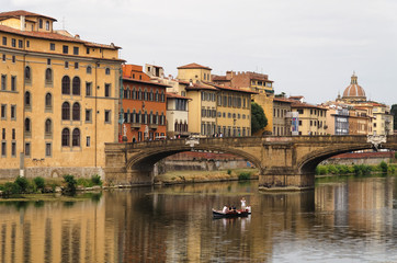 The river arno. Medieval bridge. Boat in the middle of the river. Cheap hotels in Florence, Tuscany, Italy.