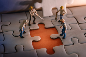 Teamwork and Solving Problem Concept. Group of Miniature Worker Men Found Something Wrong on the Work Process (a Piece of Jigsaw Puzzle)