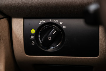 Close-up on the headlight switch control buttons,  automatic adjust level dashboard. modern car interior: parts, buttons, knobs.