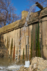 The image of a flask with clean drinking water against the background of sewage discharge.