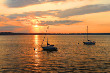 Amazing summer evening landscape with group of drifting yachts on a lake Mendota during spectacular sunset. Bright sky reflects in the lake water. Madison, Wisconsin, Midwest USA.