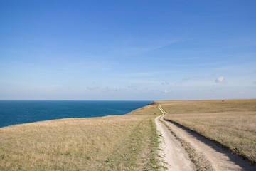 Fototapeta premium Big stones calm sea, clear sky with clouds skyline and road