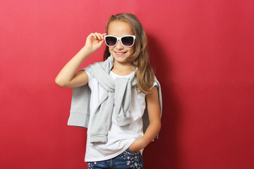 Little cheerful smiling girl in fashionable clothes on a colored background. Children's clothing, children's fashion