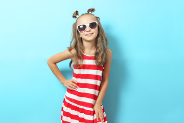 Little cheerful smiling girl in fashionable clothes on a colored background. Children's clothing, children's fashion