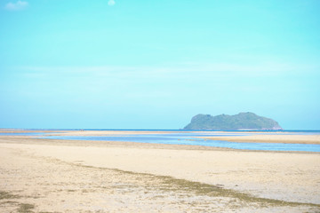 A beautiful sea beach with water run out and blurred a mountain,blue sky in bright day