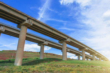 Fototapeta na wymiar Two road turn highway bridge, viaduct supports in the valley among the green hills, transport infrastructure.