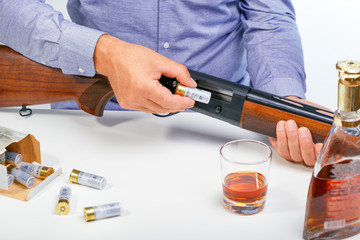 Man With Rifle And alcohol. Man hands holding gun and alcohol glass on the table. Dangerous man with a rifle. Cun control concept.