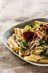 Pasta with chicken meat, sun-dried tomatoes and rucola