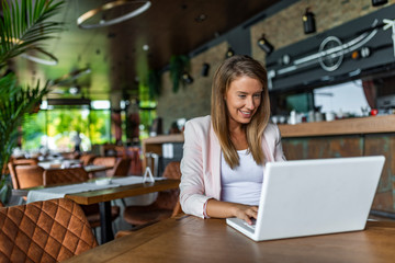 Beautiful Caucasian woman dreaming about something while sitting with portable net-book in modern cafe bar, young charming female freelancer thinking about new ideas during work on laptop computer