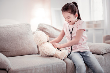 Cute joyful girl playing in a doctor