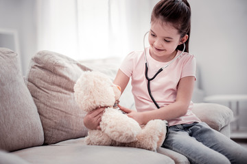 Joyful pleasant girl looking at her fluffy toy