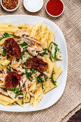 Pasta with chicken meat, sun-dried tomatoes and rucola