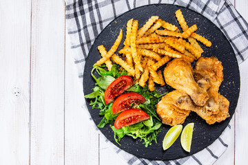 Grilled chicken drumsticks with french fries and vegetables