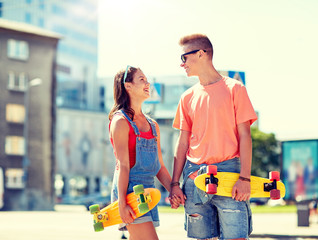 summer holidays, extreme sport and people concept - happy teenage couple with short modern cruiser...