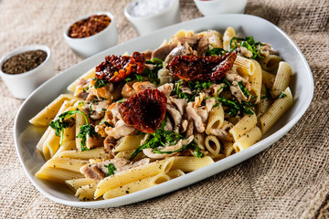 Pasta with chicken meat, sun-dried tomatoes and rucola