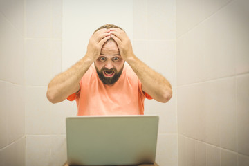 startled businessman working with laptop in toilet