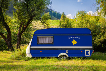 A car trailer, a motor home, painted in the national flag of  Kosovo stands parked in a...
