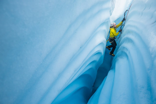 Ice climbing between canyon walls covered in wavy lines carved by meltwater.
