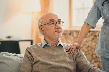 Kind doctor putting her hand on the shoulder of patient