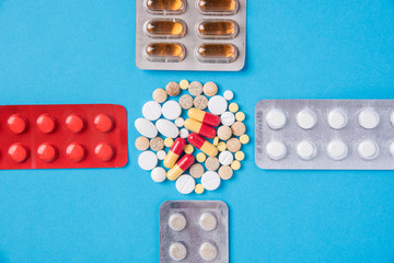Different tablets and pills in the package and without it on a blue background