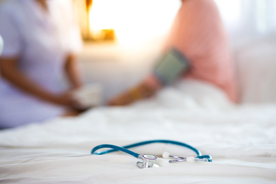 Closeup of stethoscope on blur photo of Nurse measuring blood pressure of senior woman background