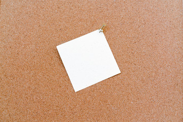 Corkboard with white color stickers fixed by a pin. Square shaped sheets stuck on a billboard by colored thumbtacks. Notice board with empty reminder note.