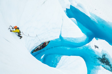 Athlete climbing out of a boat on a lake on top of the ice of the Matanuska Glacier.