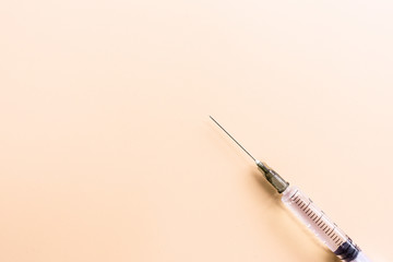 Medical syringe on pastel orange background, health and vaccination concept. Flat lay, mockup,...