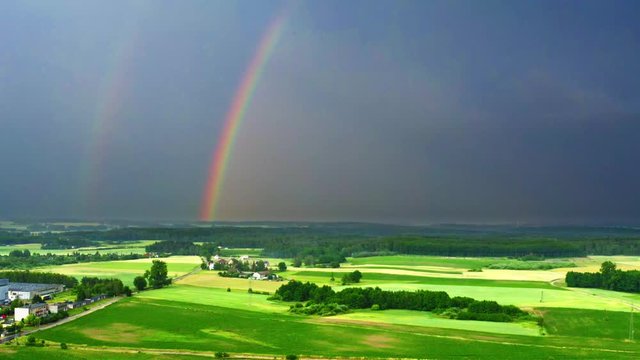 Aerial view of rainbow over green fields after a storm