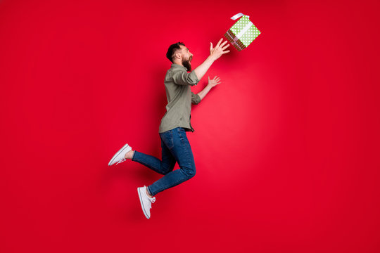Full length body size photo of man trying to catch his prize gift while isolated with red background