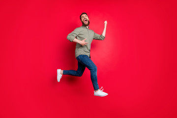 Full length body photo of cheerful playful happy glad handsome white trendy model rock musician wearing grey shirt imagining like playing guitar while isolated with red background