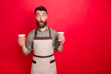 Portrait of his he nice attractive confused stunned wondered bearded guy waiter holding in hands cappuccino espresso latte choose choice isolated over bright vivid shine red background