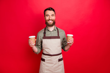 Portrait of his he nice attractive cheerful cheery content bearded guy waiter holding in hands cappuccino hot chocolate espresso isolated over bright vivid shine red background