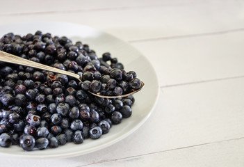blueberries in a spoon on a background of a plate with blueberries. Close-up.