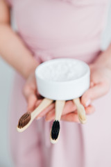 Girl holding a useful bamboo toothbrush and a jar of tooth powder
