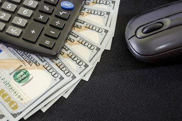 dollars, computer mouse and calculator on a black background. Close-up. Place for text.