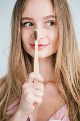 Young beautiful girl holding a useful bamboo toothbrush