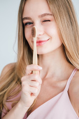 Young beautiful girl holding a useful bamboo toothbrush
